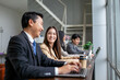 © todja - Asian business team male and female colleagues talking at work share ideas  with laptop, Happy colleagues work together on computer in office.