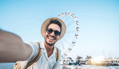 Wall Mural - Happy tourist taking selfie on summer vacation - Smiling guy looking at camera outside - Millenial taking photo with smart mobile phone - Focus on eye