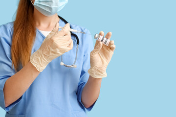 Wall Mural - Female doctor with monkeypox vaccine and syringe on blue background