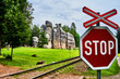 Stop sign in front of narrow-gauge railroad at a group of sandstone boulders on the lawn of the rock garden Adersbach, Czech Republic.