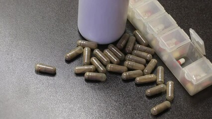 Wall Mural - Medicine in gelatin capsules. Scattered on the table. Nearby is a pill case filled with pills. Close-up.