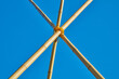 Drei verbundene Bambusstangen ragen in den blauen Himmel und halten sich gegenseitig.