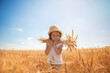 Happy girl walking in golden wheat, enjoying the life in the field. Nature beauty, blue sky and field of wheat. Family outdoor lifestyle. Freedom concept. Cute little girl in summer field