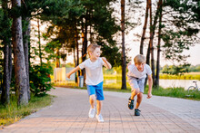 Two Boys Running And Racing Each Other Outdoors In Nature. Siblings Connection. Friends And Brothers Play. Healthy Activity For School Child.Friends And Brothers Play. Activity For School Child.