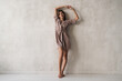 © Damir Khabirov - Full length fashion shot of woman in her home outfit, silk robe standing near wall in the morning