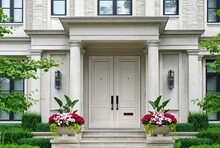 House Entrance With Columns Surrounded By Pots Of Flowers