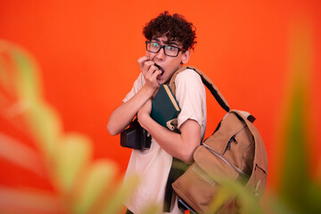 Wall Mural - Young attractive tourist with a backpack. Orange background.	