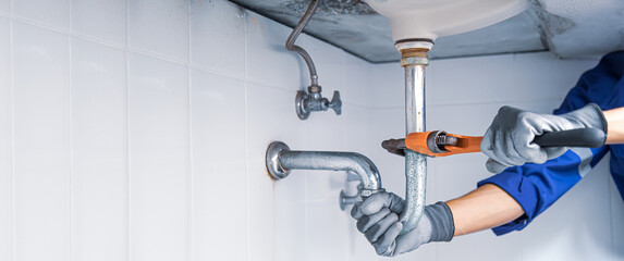 Wall Mural - Technician plumber using a wrench to repair a water pipe under the sink. Concept of maintenance, fix water plumbing leaks, replace the kitchen sink drain, cleaning clogged pipes is dirty or rusty.