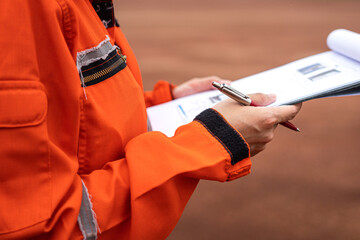 Wall Mural - A management person is holding a luxury pen, preparing to take note on paper during perform safety audit at work site. Industrial working scene action photo. Selective focus.