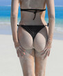 Sexy sandy woman buttocks, sexy body girl in a black bikini in the sand