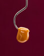 Live rosin dangling on the end of a hook with a red background. 