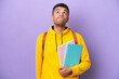 © luismolinero - Young student Brazilian man isolated on purple background and looking up
