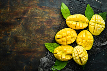 Wall Mural - Fresh tasty sweet mango with leaves on old wooden dark background. Rustic style. Top view. Tropical fruits.