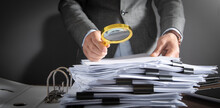 Businessman Holding Magnifying Glass With Documents.