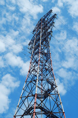 A high-voltage metal pylon against a blue cloudy sky.