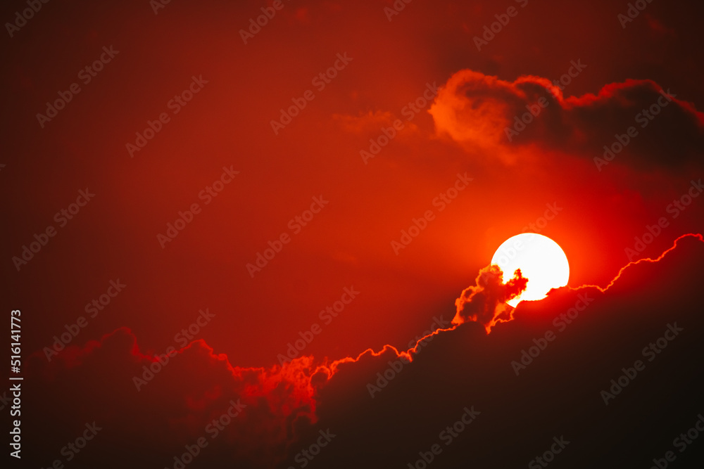 Dramatic fiery red sunset sky with a white sun and dark clouds ...