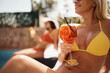 Close up of woman having cocktail on summer day at swimming pool.