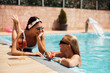 Happy women talk while spending summer day in swimming pool.