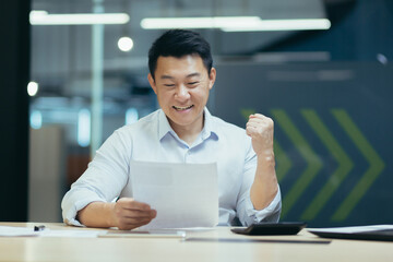 Wall Mural - Successful and confident asian businessman reading bank letter and financial report, happy and celebrating triumph success, holding hand up