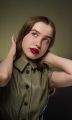 Wall Mural - Portrait of a young attractive girl with expressive red lips and long smooth hair of a light shade in a stylish green dress . Close-up, green background