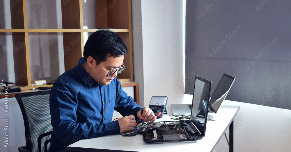 young man who is a computer technician A laptop motherboard repairman ...