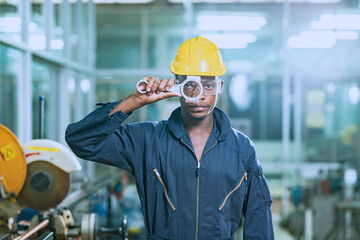 african worker Wearing a yellow safety helmet, he is confidently posing as he picks up the wrench.