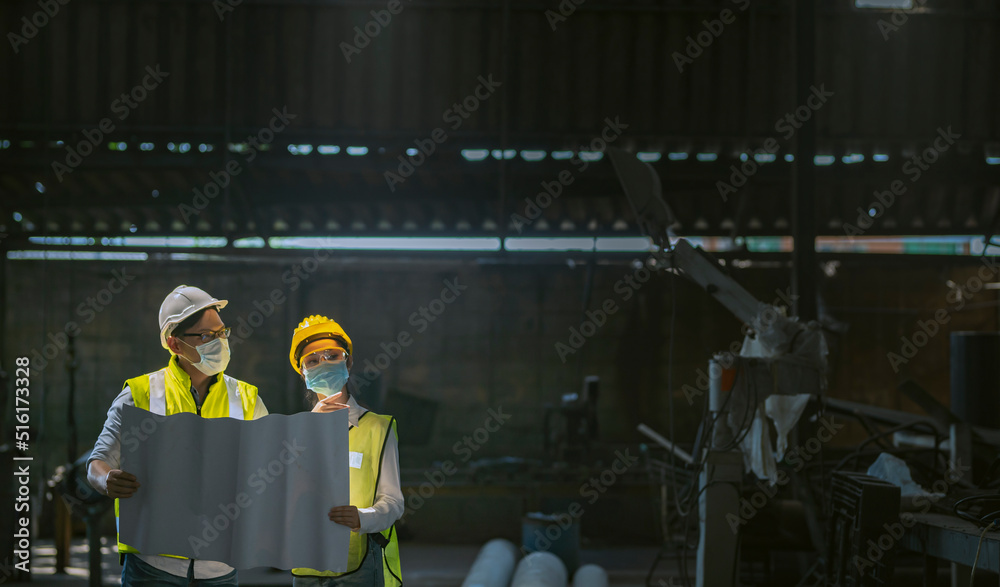 male and female engineers laying out a plan inside the factory to plan ...