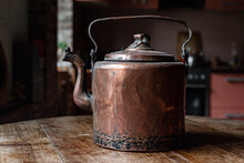 An Old Copper Kettle Stands In The Kitchen On A Wooden Table