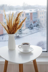 cup of coffee on white table by window on winter