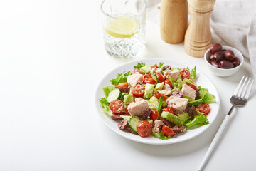 Wall Mural - Salad with tuna, lettuce, cucumbers, tomatoes, olives and avocados in white plate on the table