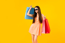 Fashion Asian Woman Holding Shopping Bags On A Yellow Background With Copy Space. Summer Sales Concepts.