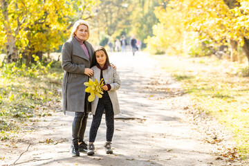 Wall Mural - happy family: mother and child little daughter play on autumn walk in nature outdoors