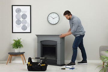 Wall Mural - Man installing electric fireplace near wall in room