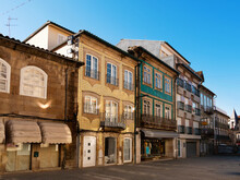 View Of Empty Narrow Street In Portuguese City Of Vila Real With Townhouses Decorated With Forged Balconies On Sunny Spring Day .