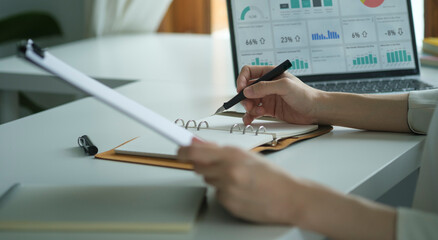 A young female administrative assistant making notes of working planning organizing information in her office.