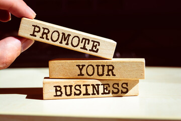 Wall Mural - Promote your business symbol. Businessman hand. Wooden blocks with words 'Promote your business'.