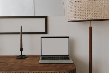 Laptop computer with blank copy space screen on table with candles, mirror and lamp. Aesthetic home office workspace. Online shopping, online store, social media, blog branding mockup template.