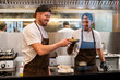 © Westend61 - Smiling chef giving plate of food to colleague