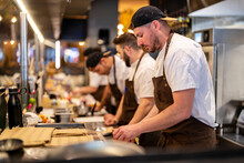 Chef Standing By Colleagues Working At Restaurant