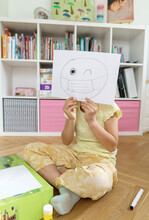 Girl Holding Paper With Emoticon Drawing At Home