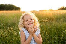 Smiling Blond Girl With Grass In Mouth Enjoying At Field