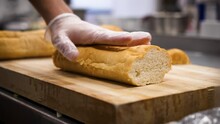 Chef slices french bread baguette, slow motion close up 4K