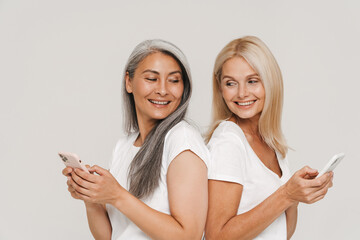 Wall Mural - Mature multiracial women smiling and holding cellphones