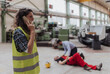 © Halfpoint - Woman is calling ambulance for her colleague after accident in factory. First aid support on workplace concept.