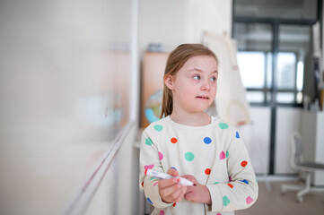 Canvas Print - Little schoolgirl with down syndrome standing in front of whiteboard