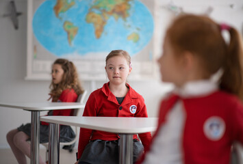 Canvas Print - Down syndrome schoolgirl paing attention in class at school, integration concept.