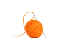Ball Of Orange Wool Yarn And A Needle With A Stretched Thread On A White Background