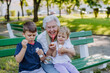 © Halfpoint - Great grandmother sitting on bench with her grandchildren and blowing soap bubbles together, generation family concept.