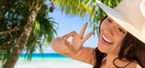 Fototapeta  - travel, tourism and summer vacation concept - happy smiling woman in straw hat showing peace gesture over tropical beach and palm trees background in french polynesia