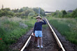 A little girl in a dress walking on an abandoned railroad tracks